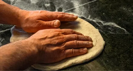 Mani che lavorano l'impasto della pizza